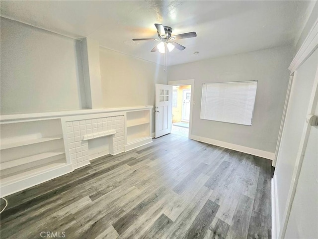 unfurnished living room featuring a ceiling fan, baseboards, and wood finished floors