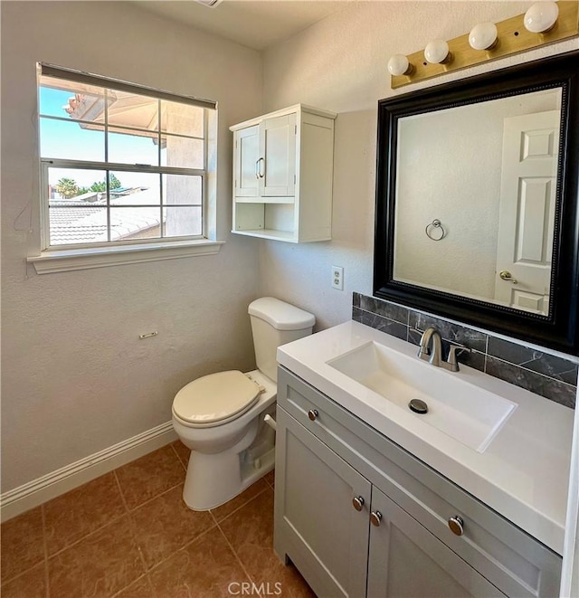 half bath featuring tile patterned floors, toilet, vanity, and baseboards
