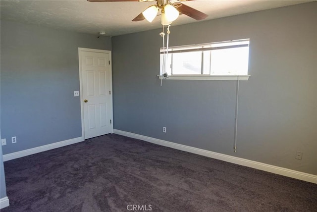 unfurnished room with a ceiling fan, baseboards, and dark carpet