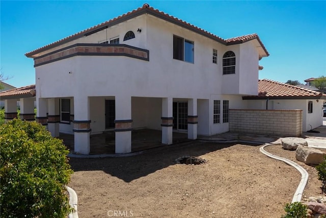 rear view of house with a tile roof, a patio area, and stucco siding