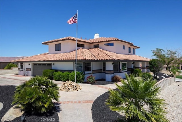 mediterranean / spanish-style home featuring a chimney, stucco siding, and a tiled roof