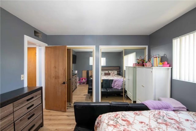bedroom featuring light wood-type flooring and two closets