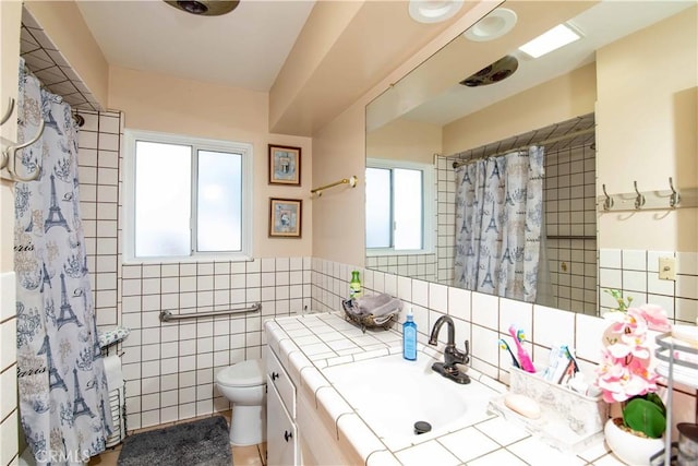 full bath with curtained shower, vanity, tile walls, and toilet
