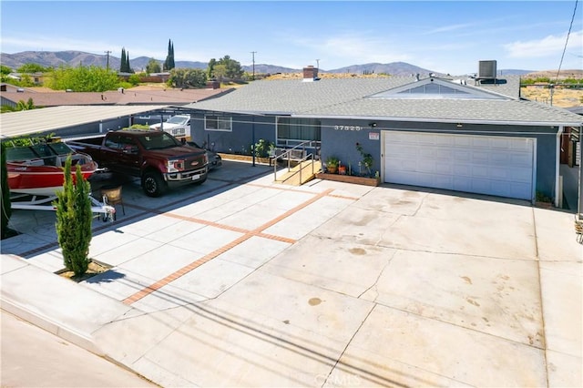 ranch-style house with a mountain view, central AC unit, driveway, and a garage