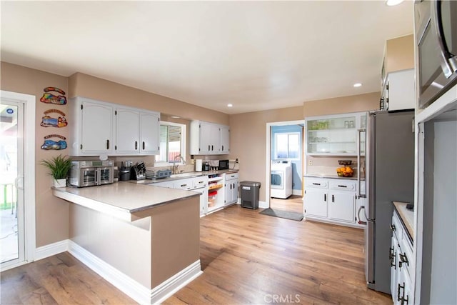 kitchen featuring washer / dryer, a peninsula, baseboards, and a healthy amount of sunlight