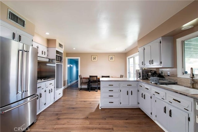 kitchen with a peninsula, a sink, stainless steel appliances, visible vents, and recessed lighting