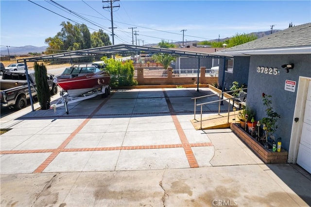 view of patio / terrace with concrete driveway, a mountain view, and fence