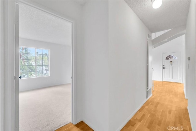 hallway with a textured ceiling and light wood-style flooring
