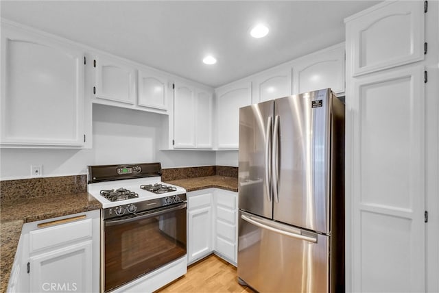 kitchen featuring freestanding refrigerator, white cabinetry, light wood-type flooring, and range with gas stovetop