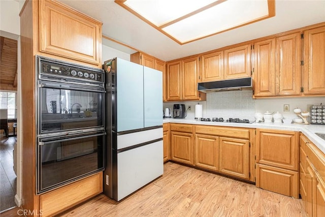 9653 La Tuna Canyon Rd, Sun Valley, CA 91352 - kitchen with light wood finished floors, black appliances, under cabinet range hood, light countertops, and decorative backsplash