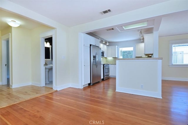 interior space featuring rail lighting, visible vents, and light wood-style floors