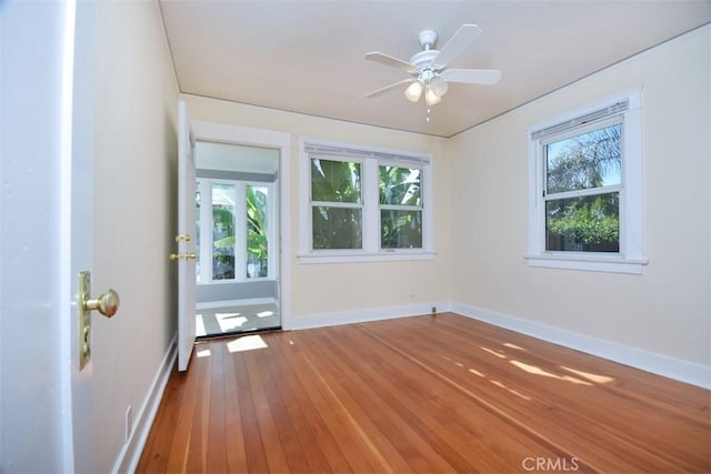 spare room with baseboards, ceiling fan, and hardwood / wood-style flooring