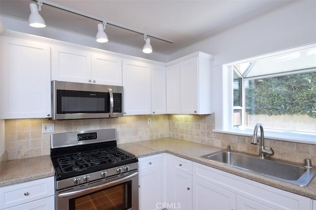 kitchen featuring a sink, stainless steel appliances, white cabinets, light countertops, and tasteful backsplash