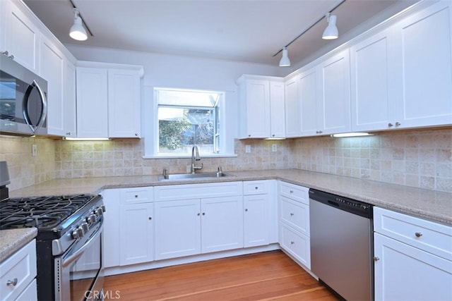 kitchen with track lighting, white cabinetry, appliances with stainless steel finishes, and a sink