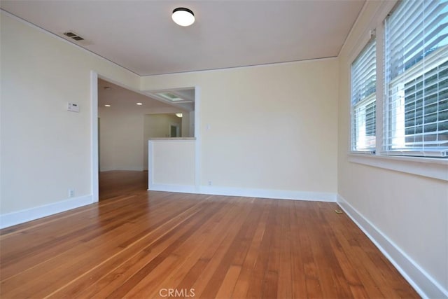 empty room featuring light wood-style floors, visible vents, and baseboards
