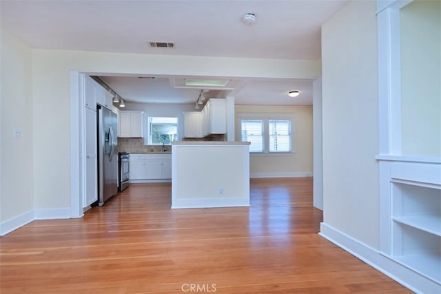 kitchen with stainless steel appliances, a healthy amount of sunlight, visible vents, light wood-style flooring, and white cabinetry