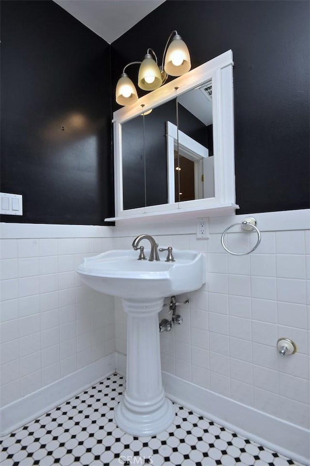 bathroom with tile walls, tile patterned flooring, and a wainscoted wall