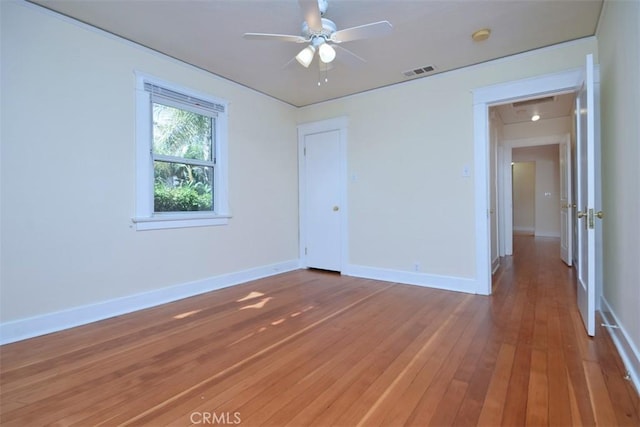empty room with ceiling fan, visible vents, baseboards, and hardwood / wood-style floors