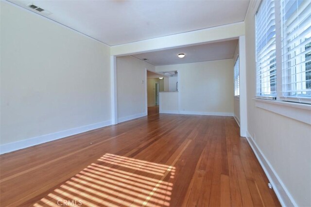 empty room with baseboards, hardwood / wood-style floors, and visible vents
