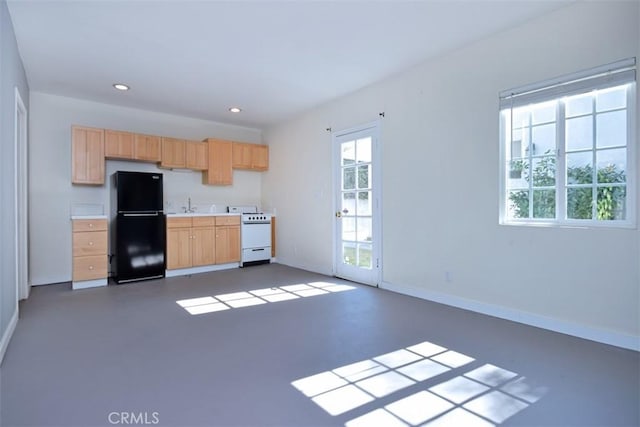 kitchen featuring a sink, freestanding refrigerator, light brown cabinets, baseboards, and gas range gas stove