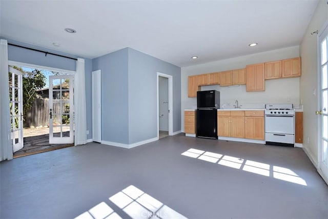 kitchen with freestanding refrigerator, light countertops, light brown cabinetry, baseboards, and white range with gas stovetop
