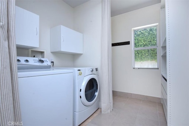 laundry area featuring baseboards, light tile patterned flooring, cabinet space, and washer and clothes dryer