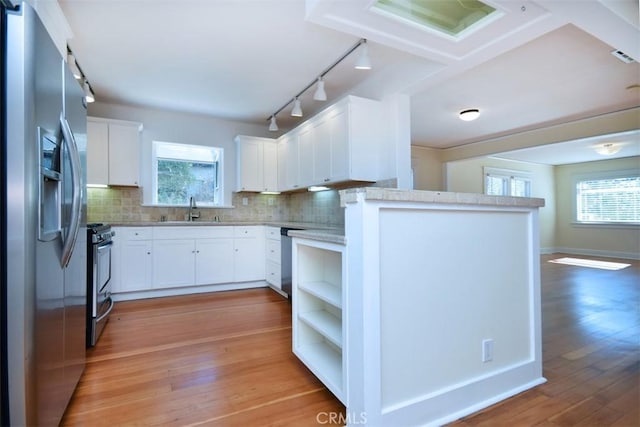 kitchen featuring light wood-style flooring, a sink, stainless steel appliances, track lighting, and white cabinets
