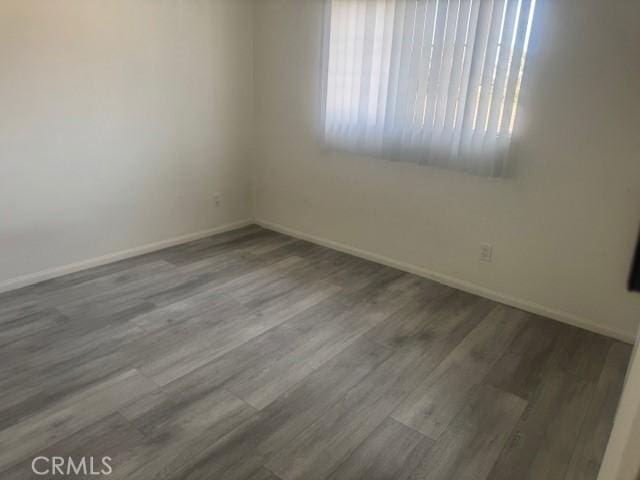 unfurnished room with baseboards and wood finished floors