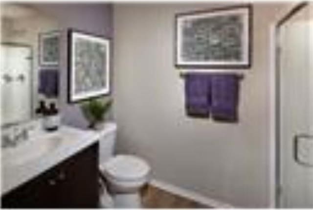 full bath featuring toilet, a shower, baseboards, and vanity