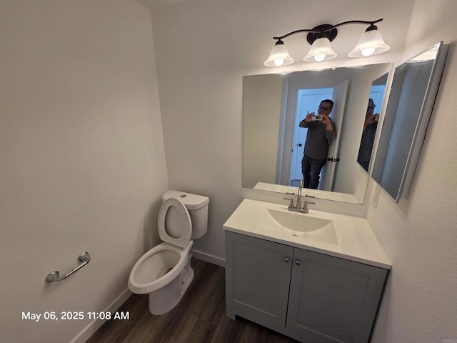 bathroom featuring baseboards, vanity, toilet, and wood finished floors
