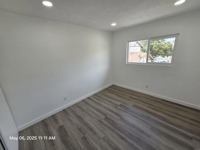 empty room featuring a textured ceiling, dark wood finished floors, baseboards, and recessed lighting