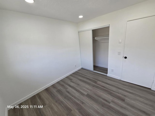 unfurnished bedroom featuring a closet, dark wood-type flooring, baseboards, and recessed lighting
