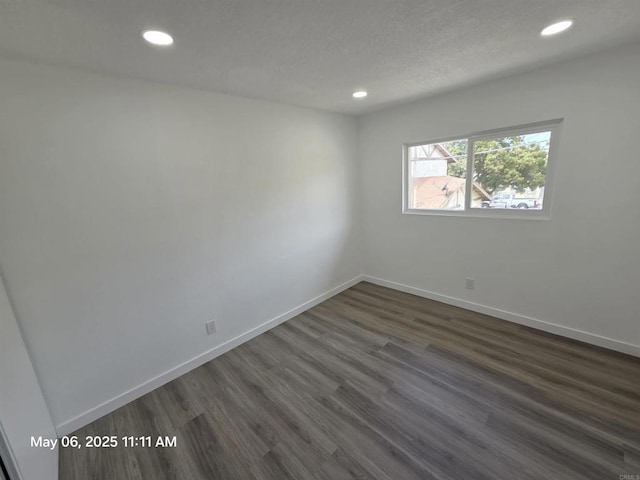 empty room with dark wood-style flooring, baseboards, and recessed lighting