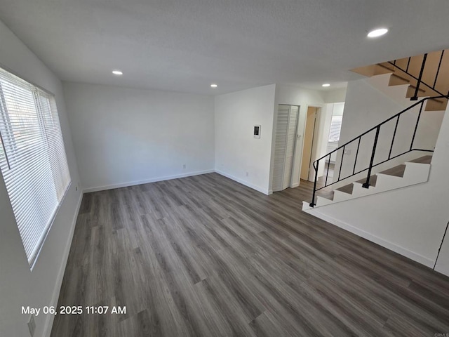 unfurnished living room featuring stairs, wood finished floors, baseboards, and recessed lighting