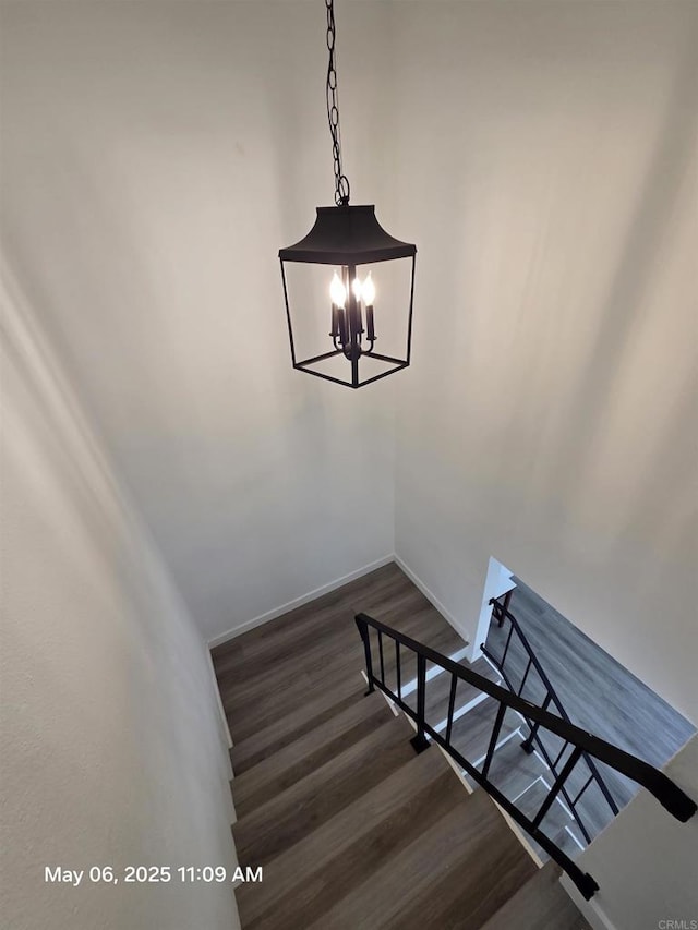 stairway featuring an inviting chandelier, baseboards, and wood finished floors