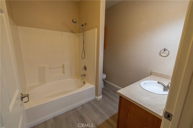 bathroom featuring shower / bathing tub combination, toilet, wood finished floors, vanity, and baseboards