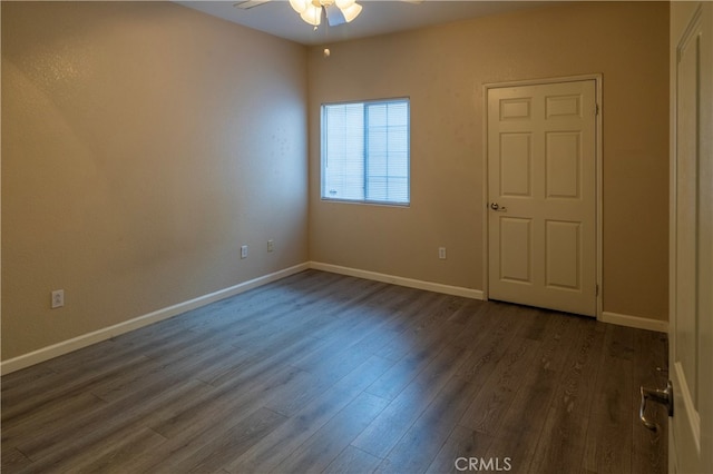 empty room featuring baseboards, ceiling fan, and dark wood-style floors