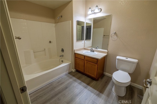 full bath with toilet, wood finished floors, washtub / shower combination, a textured wall, and vanity
