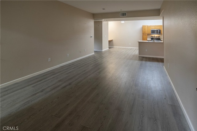 unfurnished living room with baseboards, visible vents, and dark wood-type flooring