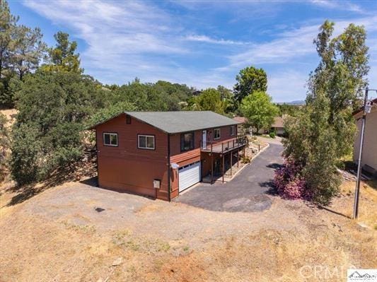 view of side of property featuring dirt driveway and a garage