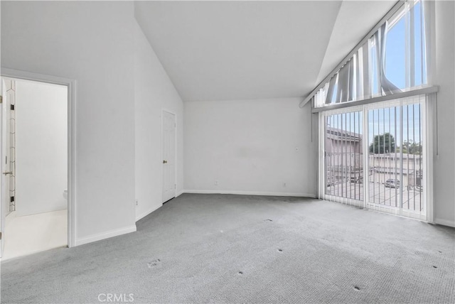 carpeted empty room featuring baseboards and high vaulted ceiling