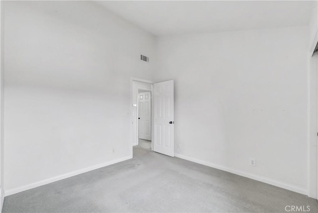 carpeted spare room featuring baseboards, high vaulted ceiling, and visible vents