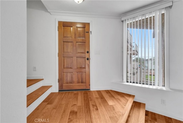 entrance foyer with baseboards, crown molding, and wood finished floors