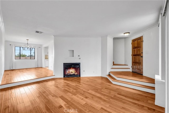 unfurnished living room featuring light wood-type flooring, ornamental molding, and visible vents