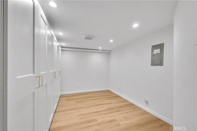 finished basement featuring electric panel, light wood-type flooring, baseboards, and recessed lighting