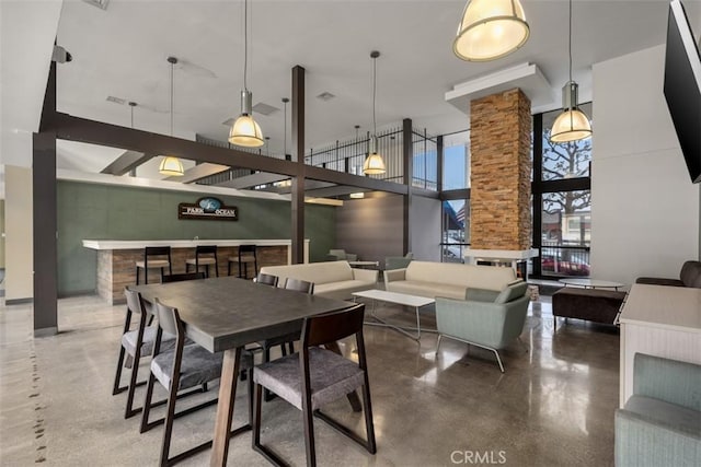 dining space with finished concrete flooring, decorative columns, and a high ceiling
