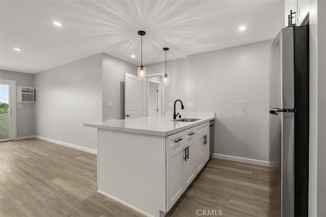 kitchen featuring light wood finished floors, a sink, white cabinetry, a peninsula, and appliances with stainless steel finishes