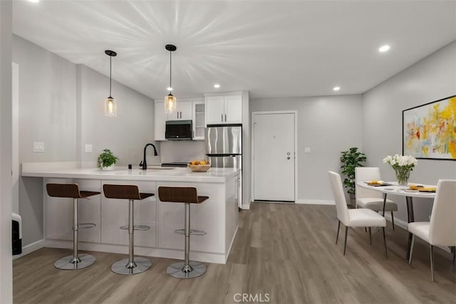 kitchen featuring light wood-type flooring, appliances with stainless steel finishes, a sink, and a kitchen bar