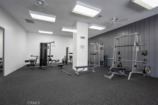 gym with a textured ceiling, a ceiling fan, and visible vents