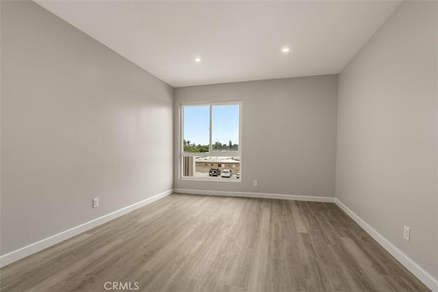 spare room with wood finished floors, baseboards, and recessed lighting